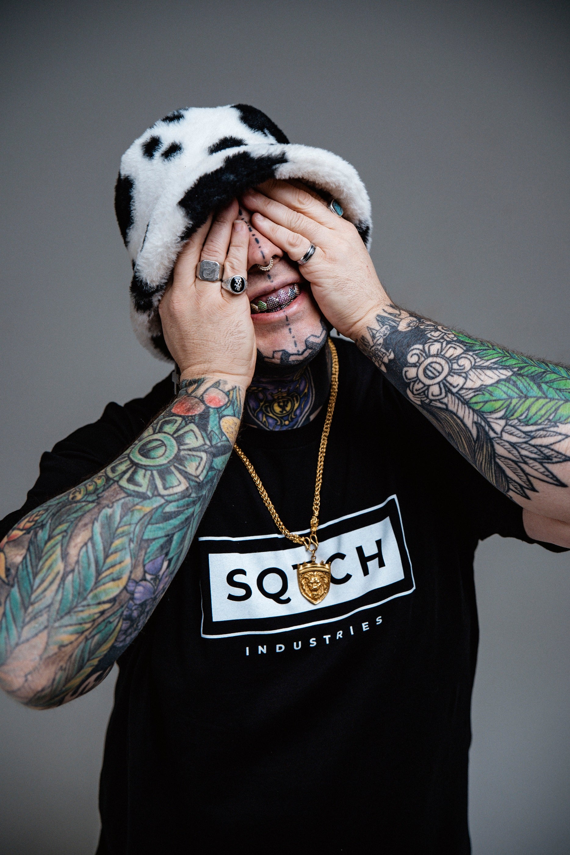 Male model wearing SQTCH Industries black streetwear hoodie with graffiti background